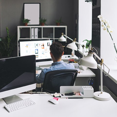 Young man working on computer while sitting at his working place in office